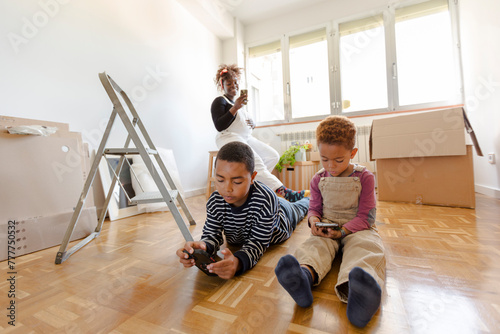 Kids playing with smartphone in new empty home photo