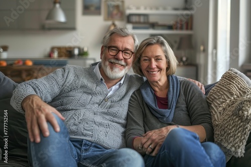 A man and woman are sitting on a couch and smiling for the camera