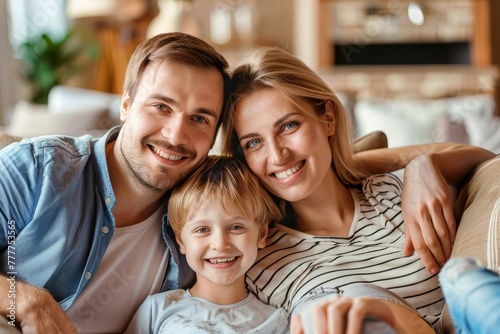 A family of three, a man, a woman and a child, are sitting on a couch