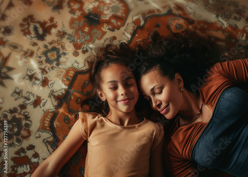 Mom and daughter lying down on a rug, overhead view