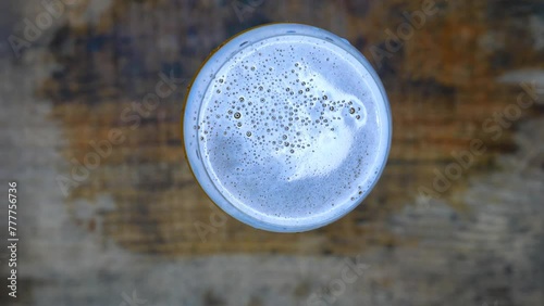 POV: person placing a big glass of cold beer on a wet wooden table. Table top view. Close-up shot: person holding a glass of bubbly beer. Person drinking beer. A glass of beer on the table. Beer day. 