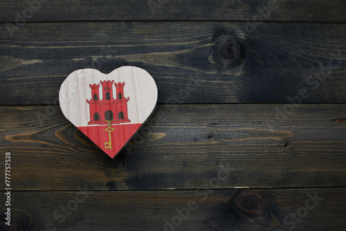 wooden heart with national flag of gibraltar on the wooden background.