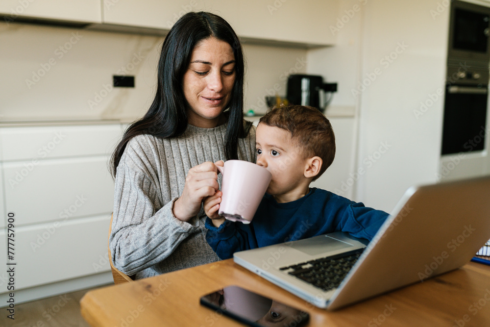 Mother giving water to son during remote work Mother giving water to son during remote work