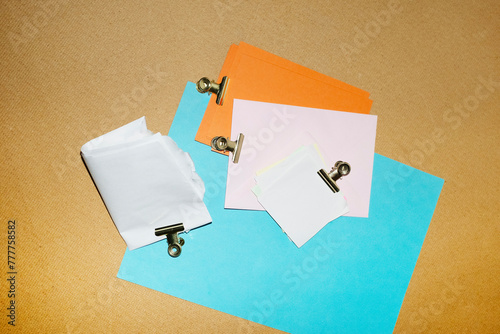 Colourful papers and post-it with golden clips in a work office photo