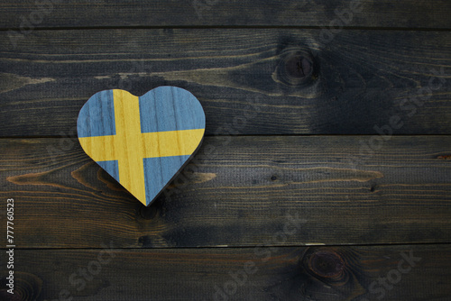 wooden heart with national flag of sweden on the wooden background.