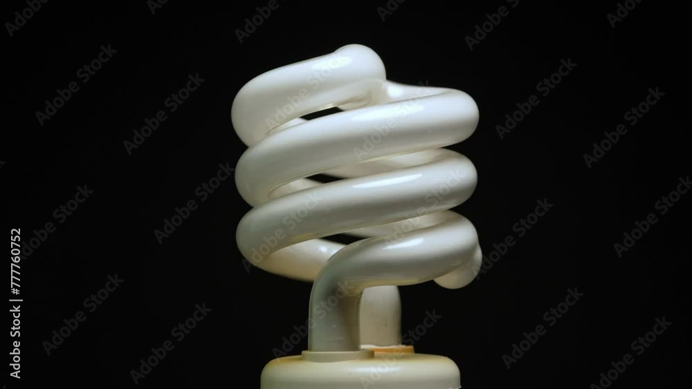 Fluorescent lamp lights close up macro view. Spiral tube bulb rotation on black background. Electric energy saving light bulb. Fluorescent lamp lights close up macro view. Spiral tube bulb rotation on black background. Electric energy saving light bulb.