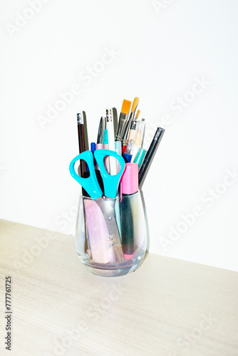 Glass filled with office supply: pencils, scissors, highlighters photo
