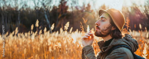 A young man with a beige Panama hat with a beard enjoys the autumn landscape in a field with tall wheat. Travel and recreation. Relaxation. Serene and free lifestyle. Banner. Copy space photo