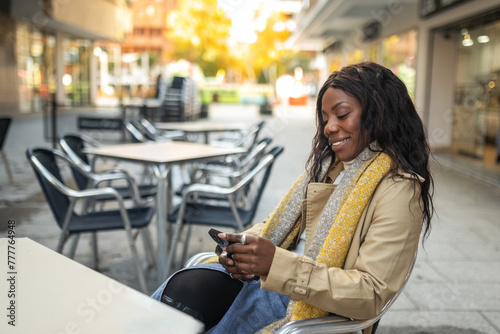 black woman using mobile phone sitting in a cafe photo