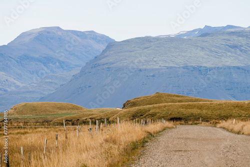 Rustic gravel path through untouched countryside against mountain photo