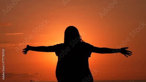  A girl makes a v sign with her hands as a sign of victory at sunset