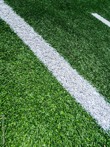 Football Field Turf. Bright green turf football field surface with white yard line markings. Angled overhead view.