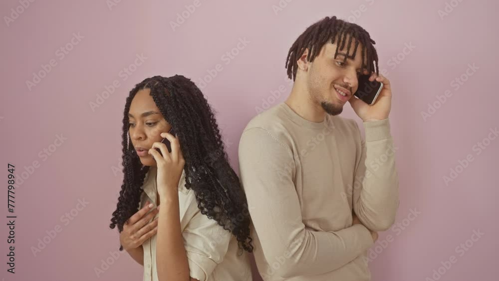 A young man and woman talk on phones against a pink wall, capturing modern communication and relationships. A young man and woman talk on phones against a pink wall, capturing modern communication and relationships.