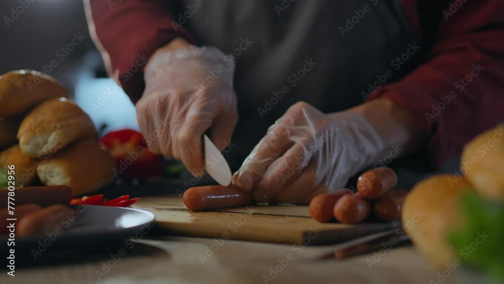 Cooking. Creative chef uses professional skills to cut sausage for cooking in fast food restaurant. Experienced worker prepares hotdogs following sustainable business principles, sausage sandwich