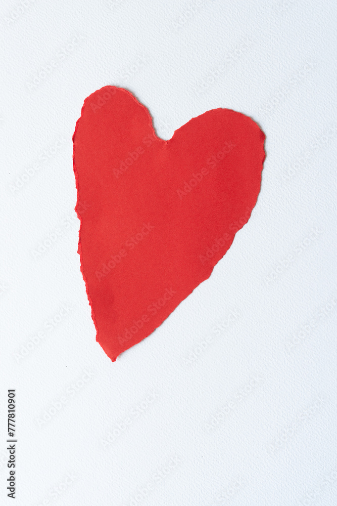somewhat stretched red paper heart with decorative torn edge isolated on blank paper