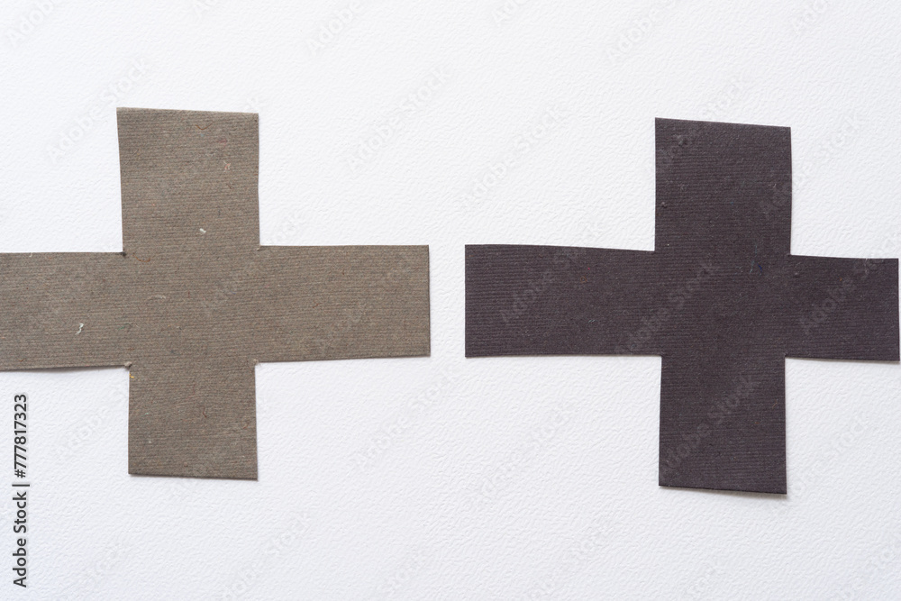 two paper crosses (or plus signs) on blank paper two paper crosses (or plus signs) on blank paper