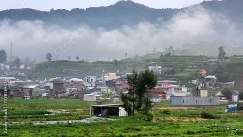 4K view of Flying through rain clouds above green mountain covered by jungle and small villages at Dieng, Central Java, Indoneisa. Wonderful rainy day. Natural landscape photo