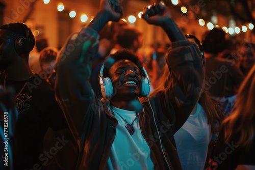 Joyful moment of a man with headphones lost in music at an outdoor event, surrounded by a crowd.