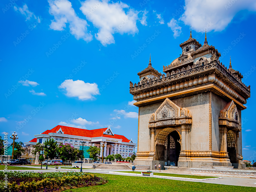 The Patuxai Victory Monument stands proudly in Vientiane, Laos, with the Prime Minister’s office in the background. The stunning structure is highlighted against a bright blue sky on a sunny day The Patuxai Victory Monument stands proudly in Vientiane, Laos, with the Prime Minister’s office in the background. The stunning structure is highlighted against a bright blue sky on a sunny day