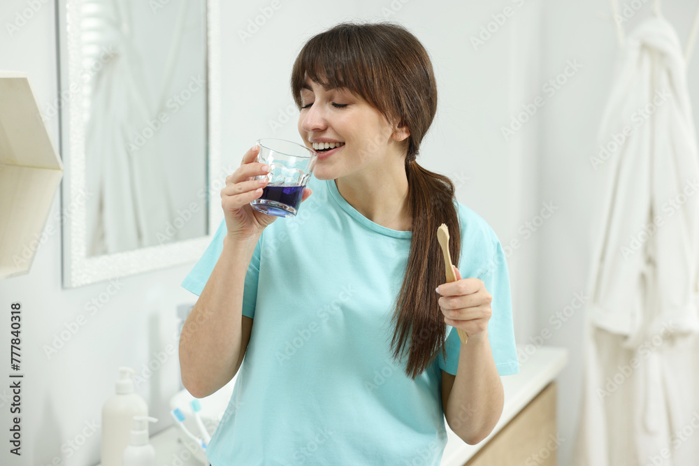 Young woman using mouthwash in bathroom. Oral hygiene Young woman using mouthwash in bathroom. Oral hygiene