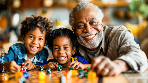 A smiling grandfather playing a board game with his two young grandchildren, sharing a joyful family moment together.