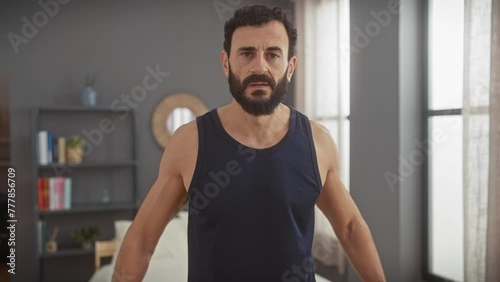 Wallpaper Mural Middle-aged bearded man wearing a tank top exercising with dumbbells in a tidy bedroom Torontodigital.ca
