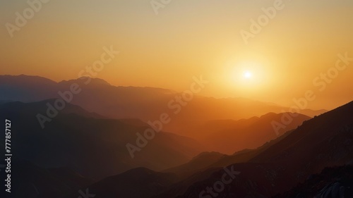 Serene mountain silhouette against the sunset sky - This image captures the tranquil beauty of layered mountain silhouettes basking in the orange glow of a setting sun