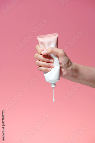 Female hand squeezes cream or gel from tube