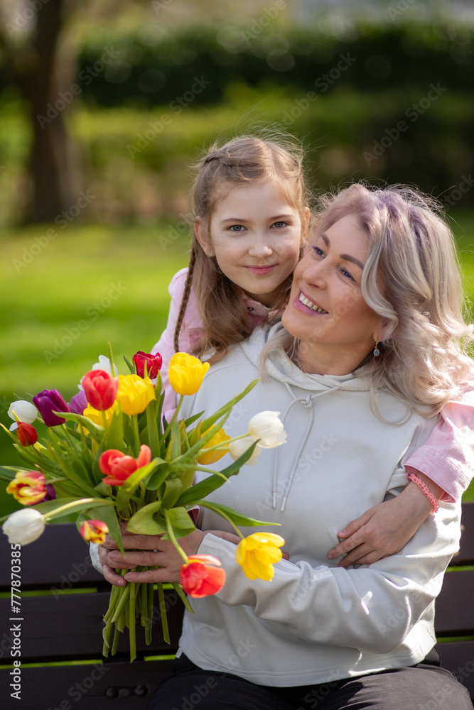 Mother and daughter smiling with tulips in park Mother and daughter smiling with tulips in park