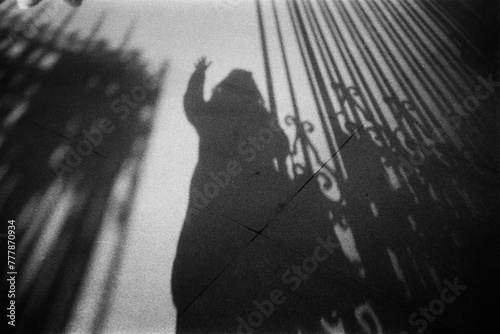 Film photography of shadow of unrecognizable person standing by gate photo