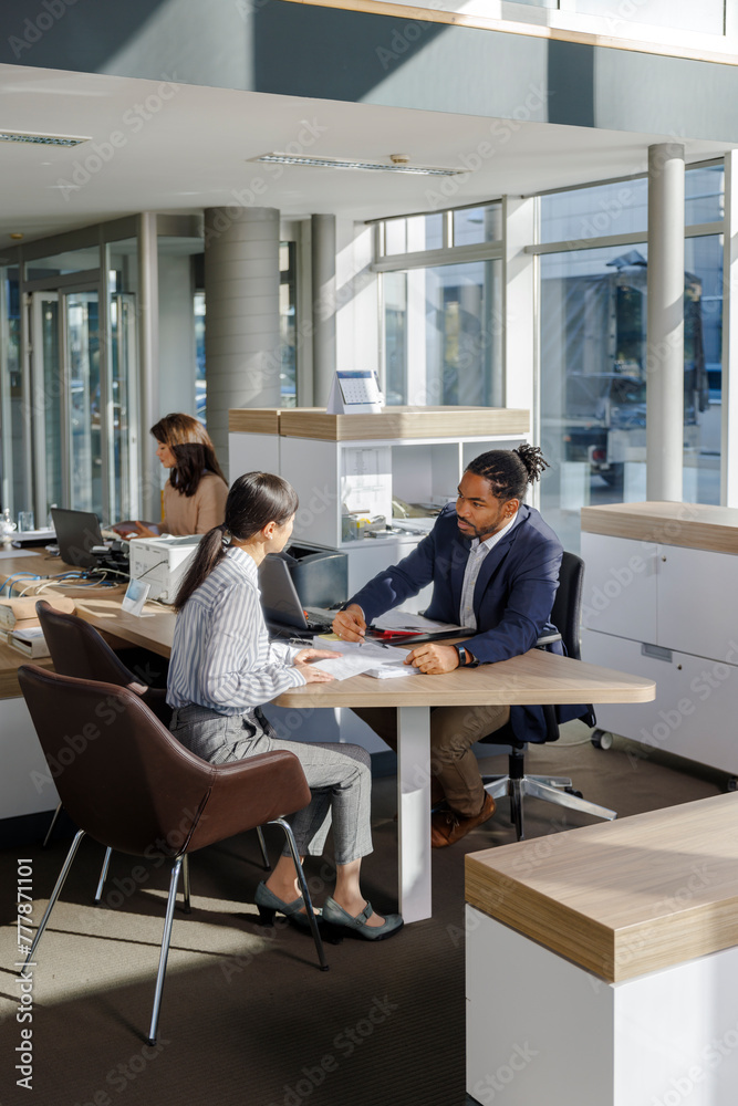 Colleagues discussing over documents at office desk
