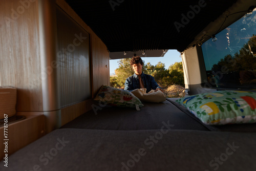 Male traveler making bed in camper photo