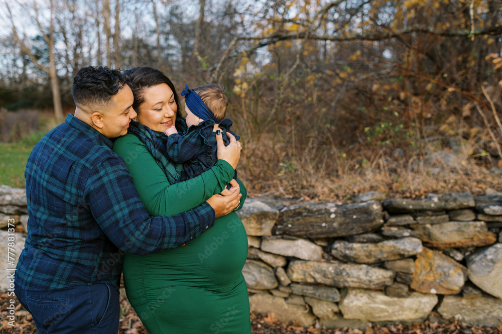 Pregnant mom and her wife holding their daughter and smiling Pregnant mom and her wife holding their daughter and smiling