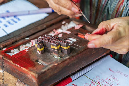 Close up of hands covered in ink preparing printing blocks with numbers and letters at Chau Doc in Vietnam