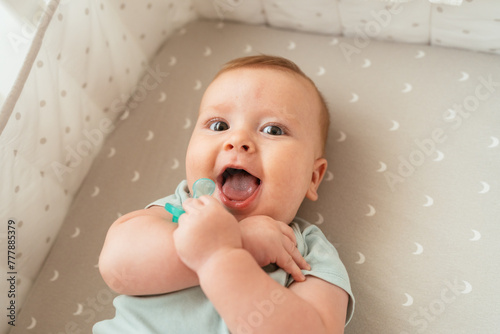 Funny infant lying in crib with pacifier