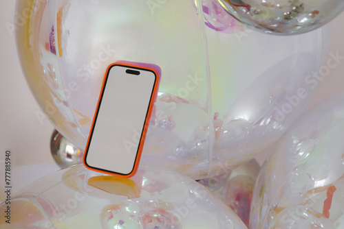 Smartphone with blank screen placed on glassy decorative ball