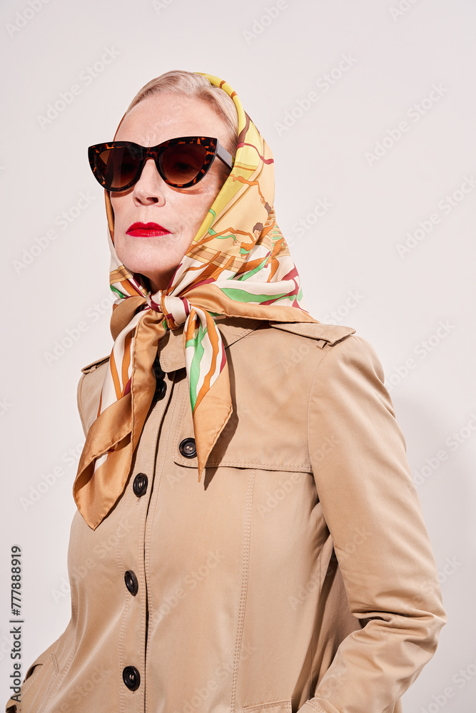 Stylish senior model wearing beige trench coat and vintage glasses Stylish senior model wearing beige trench coat and vintage glasses