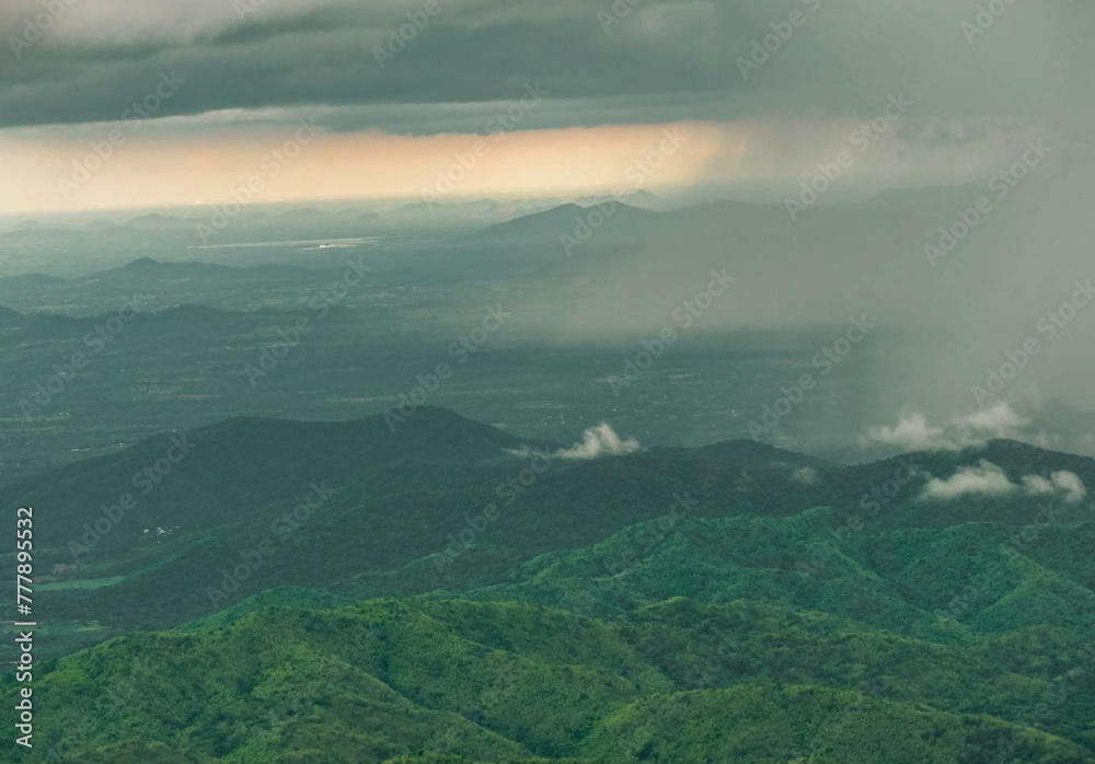 a green mountain range with a rain cloud in the background