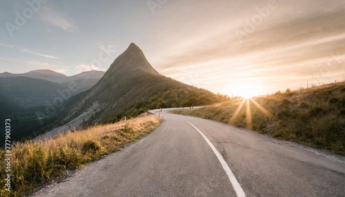 road on a hillside near mountain peak at sunset