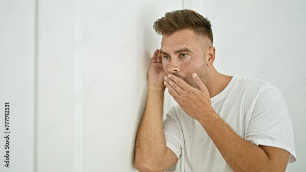 A surprised hispanic man with a beard spies through a white door in an indoor setting, showing curiosity and shock. A surprised hispanic man with a beard spies through a white door in an indoor setting, showing curiosity and shock.