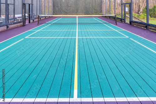 Elevated Platform Tennis, Paddle Ball courts with yellow pickelball lines, net and chicken wire fence.  Floor surface is green, maroon, with white and yellow   © Thomas