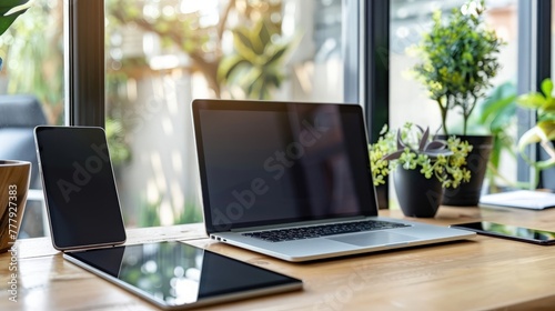 Office workplace with open laptop mockup tablet computer and smartphone on the wooden desk.