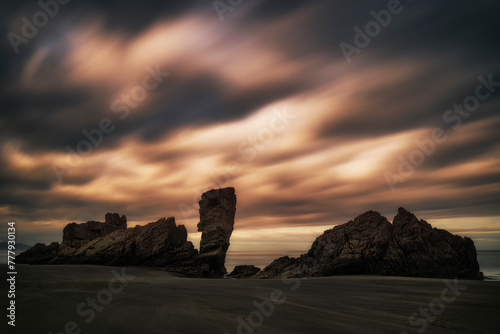 Dramatic sunrise at Playon de Bayas, Asturias beach with a sky loaded with warm-colored clouds photo