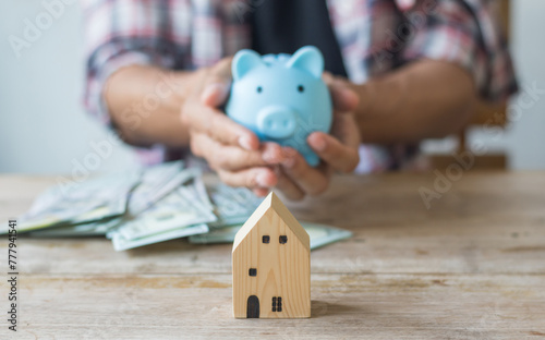 Hand's man holding money behind small house,saving concept,soft focus.