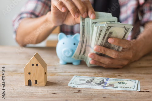 Hand's man holding money behind small house,saving concept,soft focus.