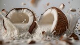 A split coconut with pieces flying and milk splashing against a neutral background, depicting freshness and tropical flavor.
