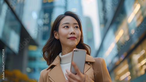 asian happy businesswoman use smartphone while she standing on sidewalk in the city