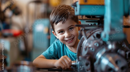 A smiling young boy in a workshop, peeking out from behind machinery, with industrial equipment blurred in the background.