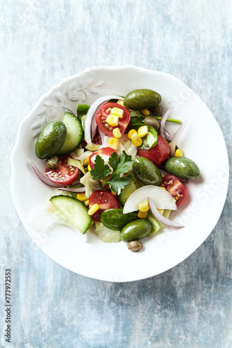 Simple Salad with Green Olives, Cucumber, Cherry Tomatoes and Capers. Bright wooden background. Top view.