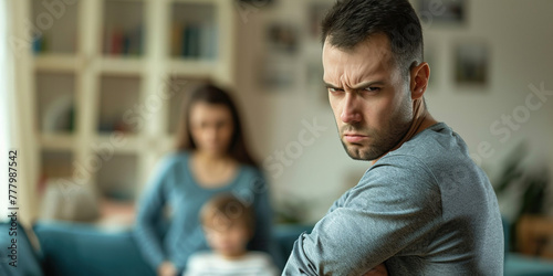 Scared mother and child sitting together on couch in scare. Selective Focus on male hand. Anger abuse and domestic violence concept. Man threatening wife and kids with his fist